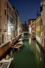 Obraz na płótnie Canvas Narrow canal with boats and vintage houses at dusk. Venice city at night
