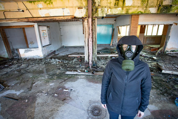 Dramatic portrait of a woman wearing a gas mask in a ruined building.