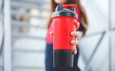 Naklejka premium Young sporty woman with protein shake outdoors, closeup