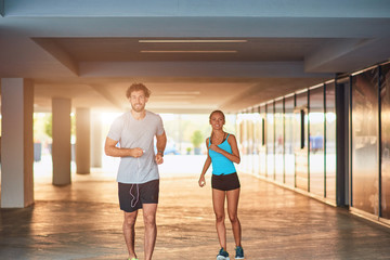 Modern woman and man jogging / exercising in urban surroundings.