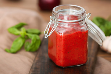 Jar of tomato sauce on wooden table