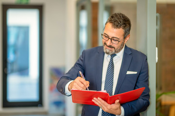 A charismatic, bespectacled bank employee takes notes on his red file
