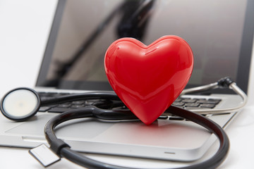 Red heart and stethoscope on laptop