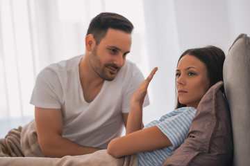 Couple is arguing in bed. Woman is offended and angry.