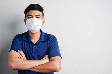 Asian smart, confident and healthy man wear medical mask to prevent pollution, virus in pain grey bakground.