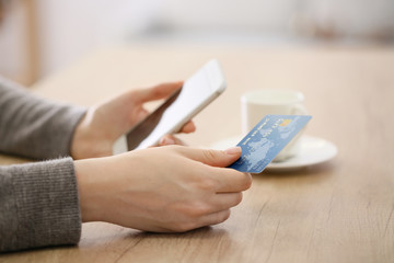 Woman using mobile phone for online banking at table