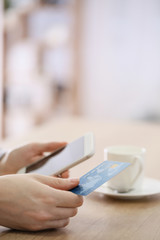 Woman using mobile phone for online banking at table