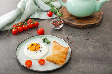 Plate with fried egg and toasted bread on grey background