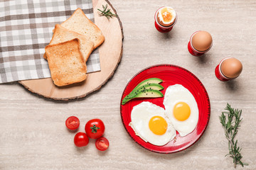 Plate with fried eggs, vegetables and toasted bread on table