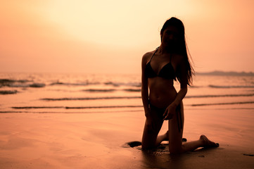 Fototapeta premium Silhouette of girls were bikini are in sexy pose, sunset in the background. Summer vacation relaxation, travel, nature, happy life unseen concept.