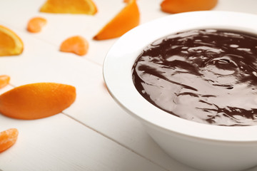 Bowl with tasty chocolate fondue and citrus fruits on white table, closeup