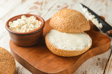 Fototapeta na wymiar Fresh bun with tasty cream cheese on table