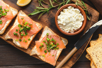 Sandwiches with tasty cream cheese and salmon on table
