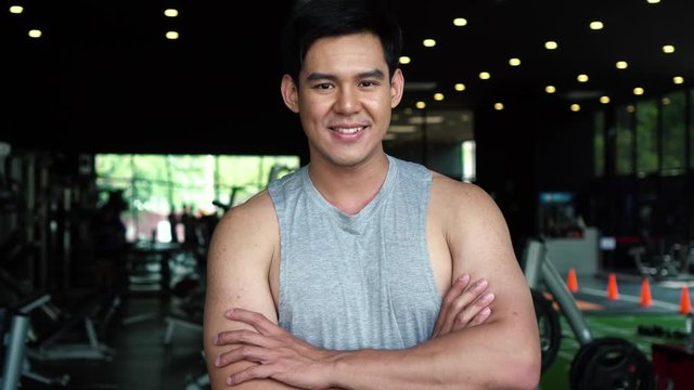 Motivated healthy young Asian sportsman looking at camera while standing at gym fitness center.