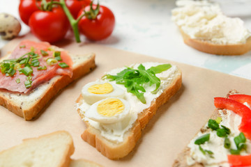 Different sandwiches with tasty cream cheese on table, closeup