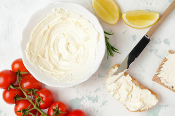Bowl with tasty cream cheese and bread on white background