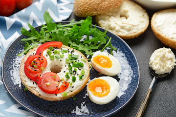 Fototapeta na wymiar Fresh bun with tasty cream cheese, eggs and vegetables on plate