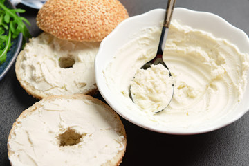 Bowl with tasty cream cheese and buns on dark background