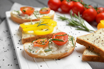 Sandwiches with tasty cream cheese and vegetables on board