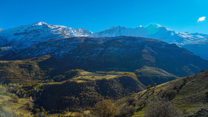 Naklejka na ściany i meble a view of mountains covered with snow in the fall season in the north of Iraq Kurdistan Region with green landscape and trees in the foreground