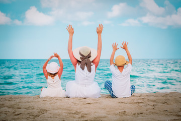 happy mom with two kids hands up on the beach