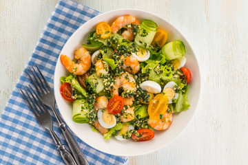 Salad with grilled shrimps, fresh lettuce, cucumbers, cherry tomatoes and quail eggs with pesto sauce.