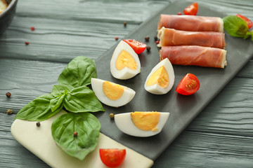 Board with tasty boiled eggs and meat on table