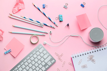 Computer keyboard with stationery on pink background