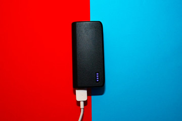 Powerbank charging on a blue and red background.