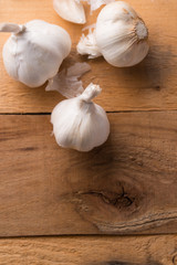 A lot of garlic on a wooden background, top view. Background for design. Vertical photo with space