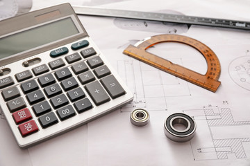Bearings with calculator, protractor and drawings on table of engineer