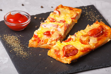 Pizza with tomatoes, cheese and tomato ketchup on a stone flat board on a gray background