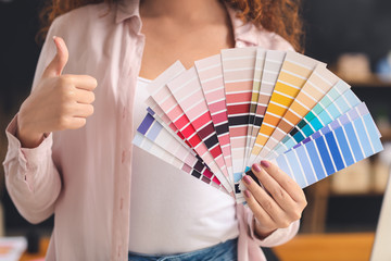 African-American designer with color palettes showing thumb-up in office