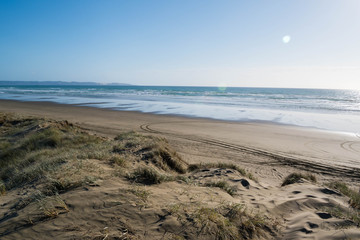Ninty Mile Beach,  North Island, New Zealand. Beautiful,  sandy, very wide, large beach with grass and tire  tracks