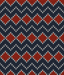 Fototapeta na wymiar Winter pattern. Seamless knitted texture with rhombuses and zigzag lines in dark blue, bright red, and white for socks, mittens, or other modern textile design.