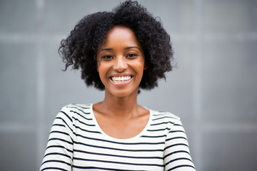 Fototapeta premium Close up beautiful young african american woman smiling by gray wall