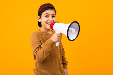 attractive european boy with a megaphone in his hands for a poster on an orange studio background