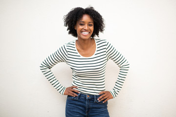 smiling young beautiful black woman with hands on hip against white background