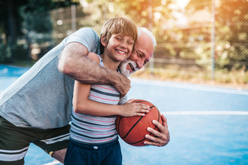 Grandfather and his grandson playing basketball.