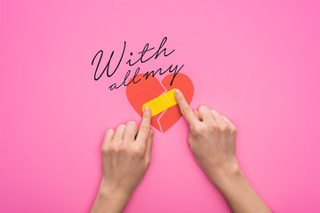cropped view of woman putting patch on broken paper heart isolated on pink background with all my...