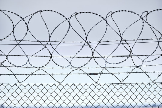 Close-up of a high chain-link fence with razor-barbed wire at the top protecting an airport in Germany