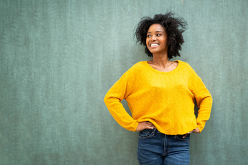 happy african american woman smiling with hands on hips against green background