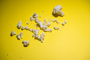 Smashed cauliflower on yellow background. Conceptual picture. Top view.