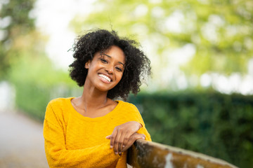 Close up of happy young black woman relaxing on bench outdoors