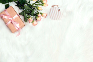 Rose flowers, gift box and decorative heart on white fur background. Place for text, top down composition.