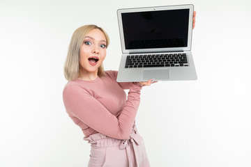 young european girl in a pink blouse demonstrates a laptop display with a mockup on a white...