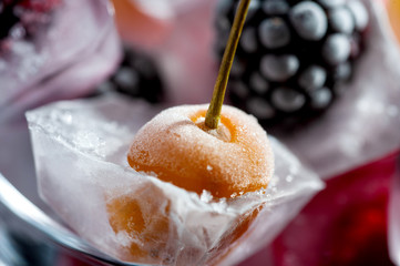  frozen raspberries berries cherries and blackberries in pieces of ice in a glass bowl on a black background