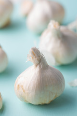 A lot of garlic on a light blue background, top view. Background for design. vertical photo