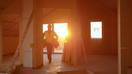 LENS FLARE: Builder carries rolls of hoses across a floor under construction