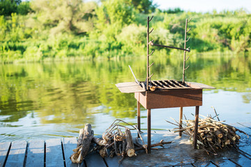 Barbecue grill with wood on the river in beautiful nature, on a raft